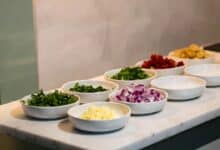 Chef-style mise en place setup on marble kitchen counter with prep bowls and fresh herbs