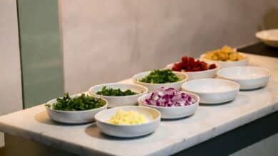 Chef-style mise en place setup on marble kitchen counter with prep bowls and fresh herbs