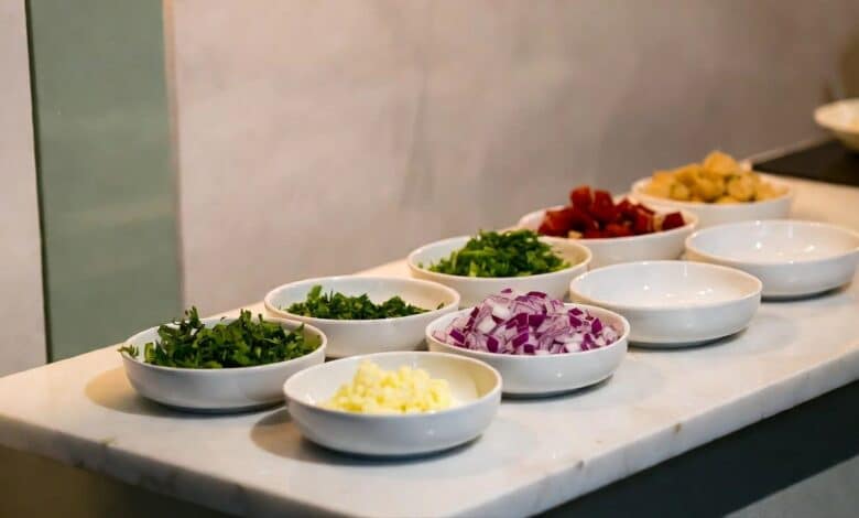 Chef-style mise en place setup on marble kitchen counter with prep bowls and fresh herbs