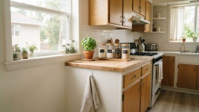 Small rental kitchen styled with a linen towel, potted herb, and matching jars
