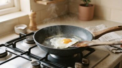 A nonstick frying pan on a stovetop with an egg cooking and sliding freely across the surface